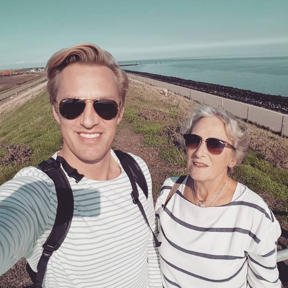 Selfie with his mother on a coastal path, both wearing striped tops.