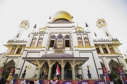 The golden-domed Sultan Mosque in Singapore under a clear sky.