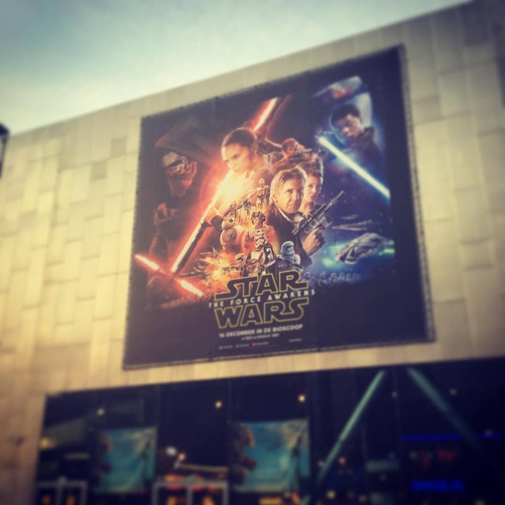 A large outdoor poster advertising the Star Wars: The Force Awakens film on the side of a building.