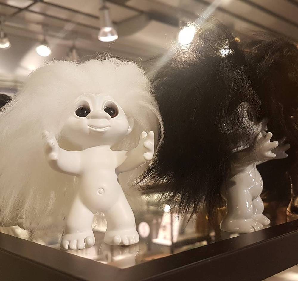 Two white and dark-haired troll figurines displayed in a shop window.