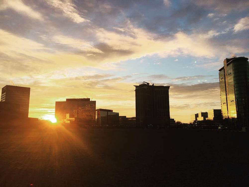 Silhouetted high-rise buildings against a golden sunset sky.