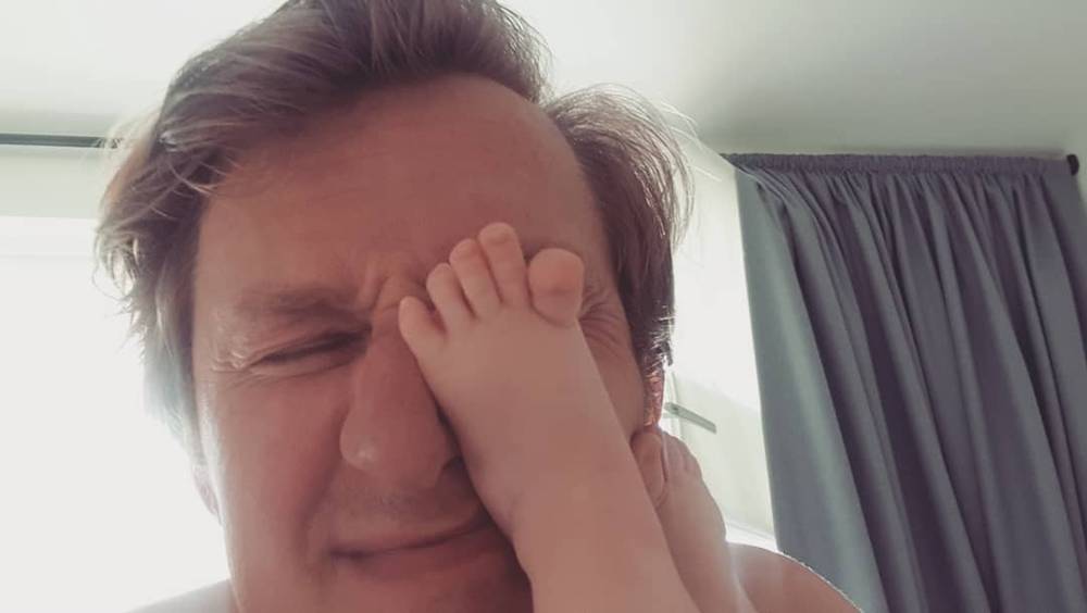 A man rubs his eye, looking tired, indoors.