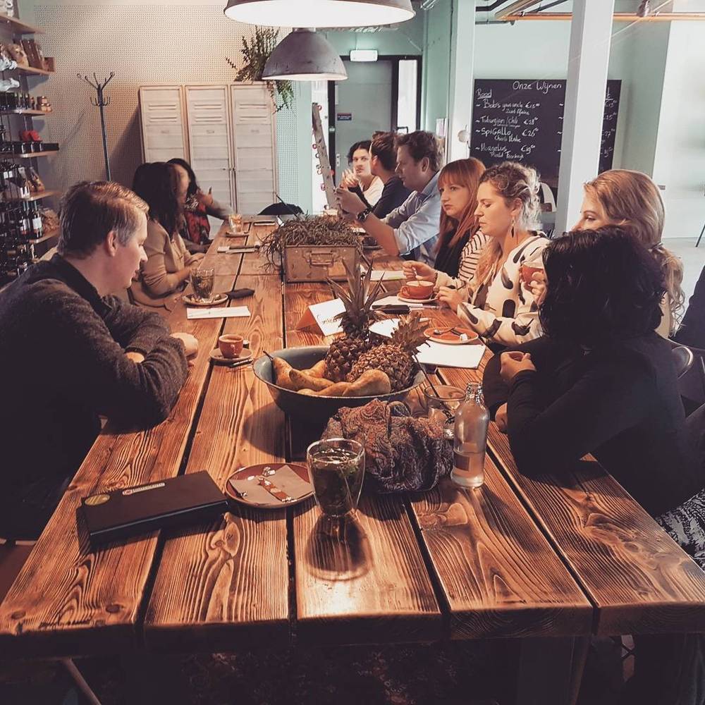 A group of colleagues having dinner together at a long wooden table.