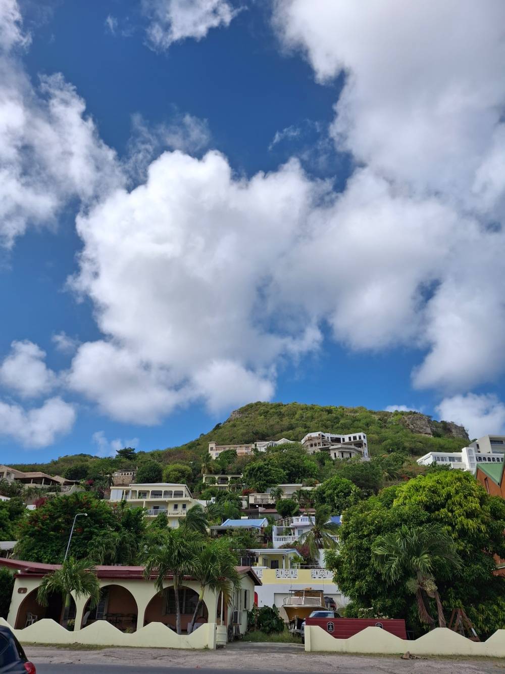 blue skies white clouds and colourful caribbean homes.. view a hill