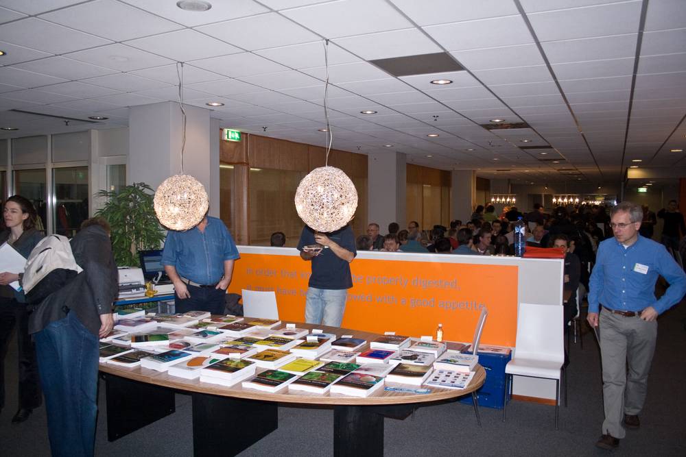 Attendees browse a display of books and materials at a conference exhibit stand.