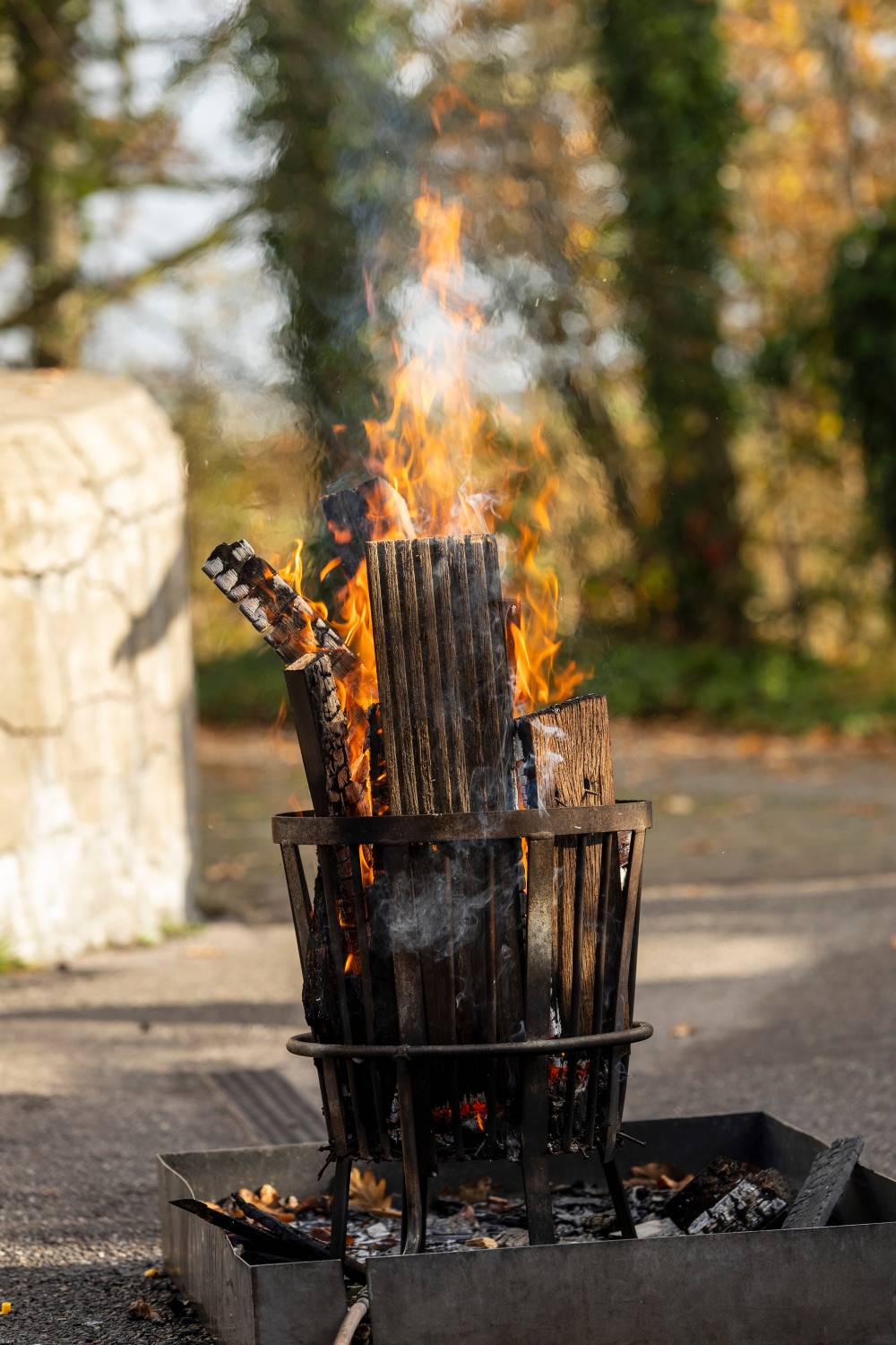 A small fire burns in a metal brazier outdoors.