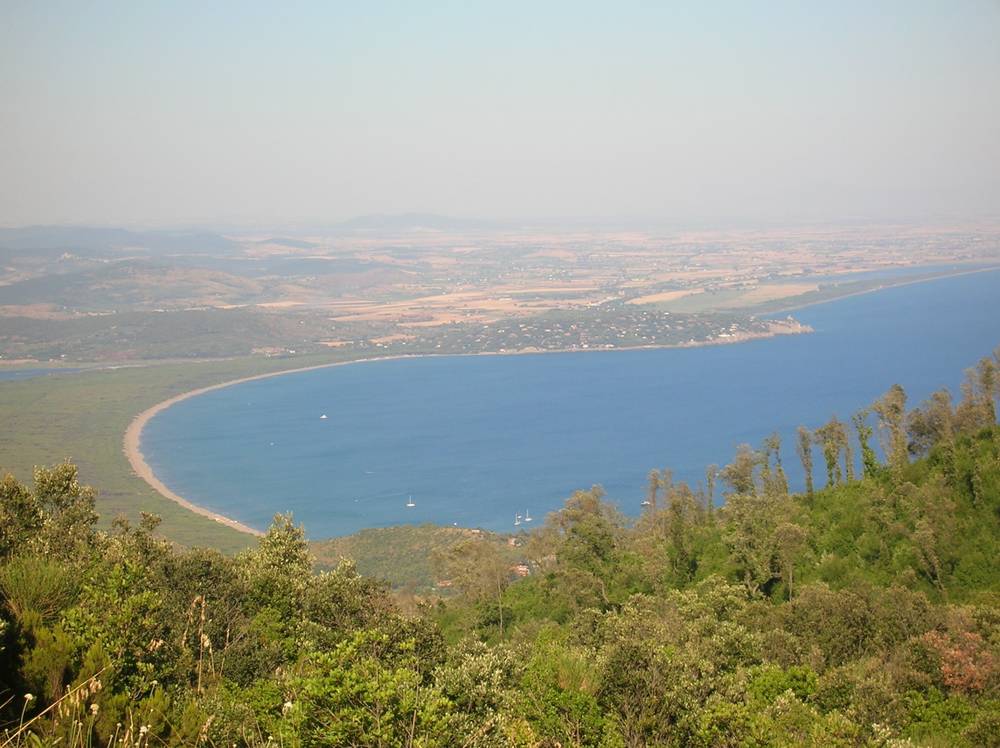 A causeway connects a lagoon to the mainland, seen from a hillside above Orbetello, Italy.