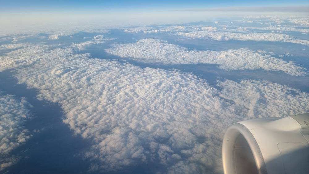 Clouds seen from an airplane window with the engine visible.