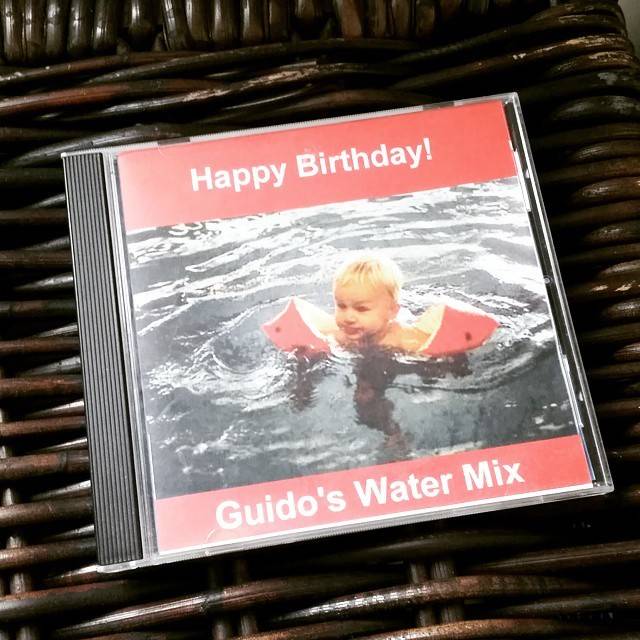 A CD case reading 'Happy Birthday! Guido's Water Mix' with a photo of a child swimming with inflatable armbands.
