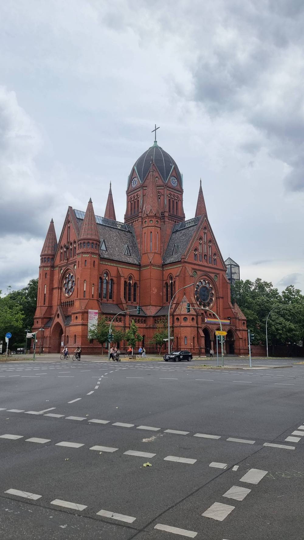 A red-brick church with a tall tower under a cloudy sky.