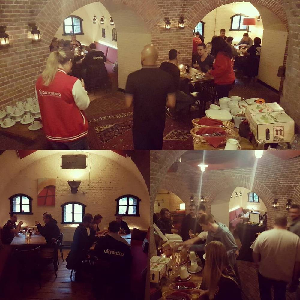 Guests dining in a brick vaulted room at an event, with staff serving food.