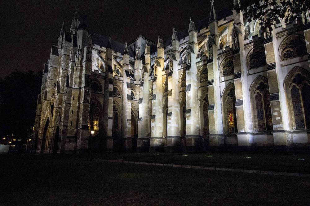 The gothic side elevation of Westminster Abbey is lit up at night.