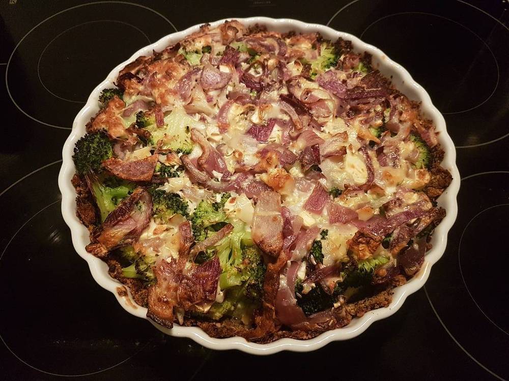 A baked savory pie topped with broccoli, bacon and cheese.