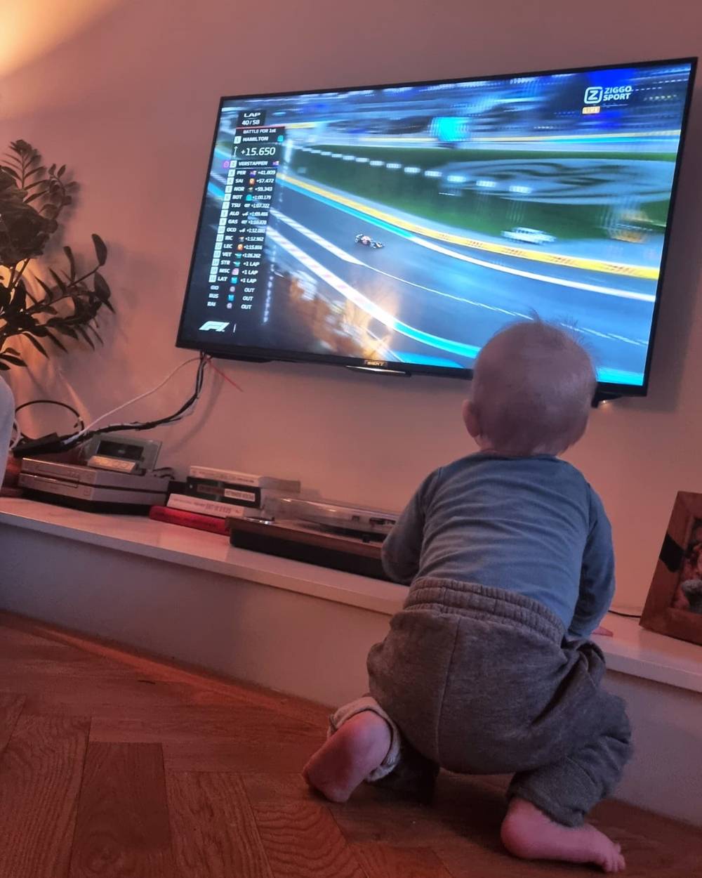 A toddler crawling toward a TV screen displaying a racing video game.