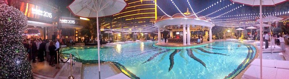 An outdoor hotel pool decorated with string lights for an evening party.