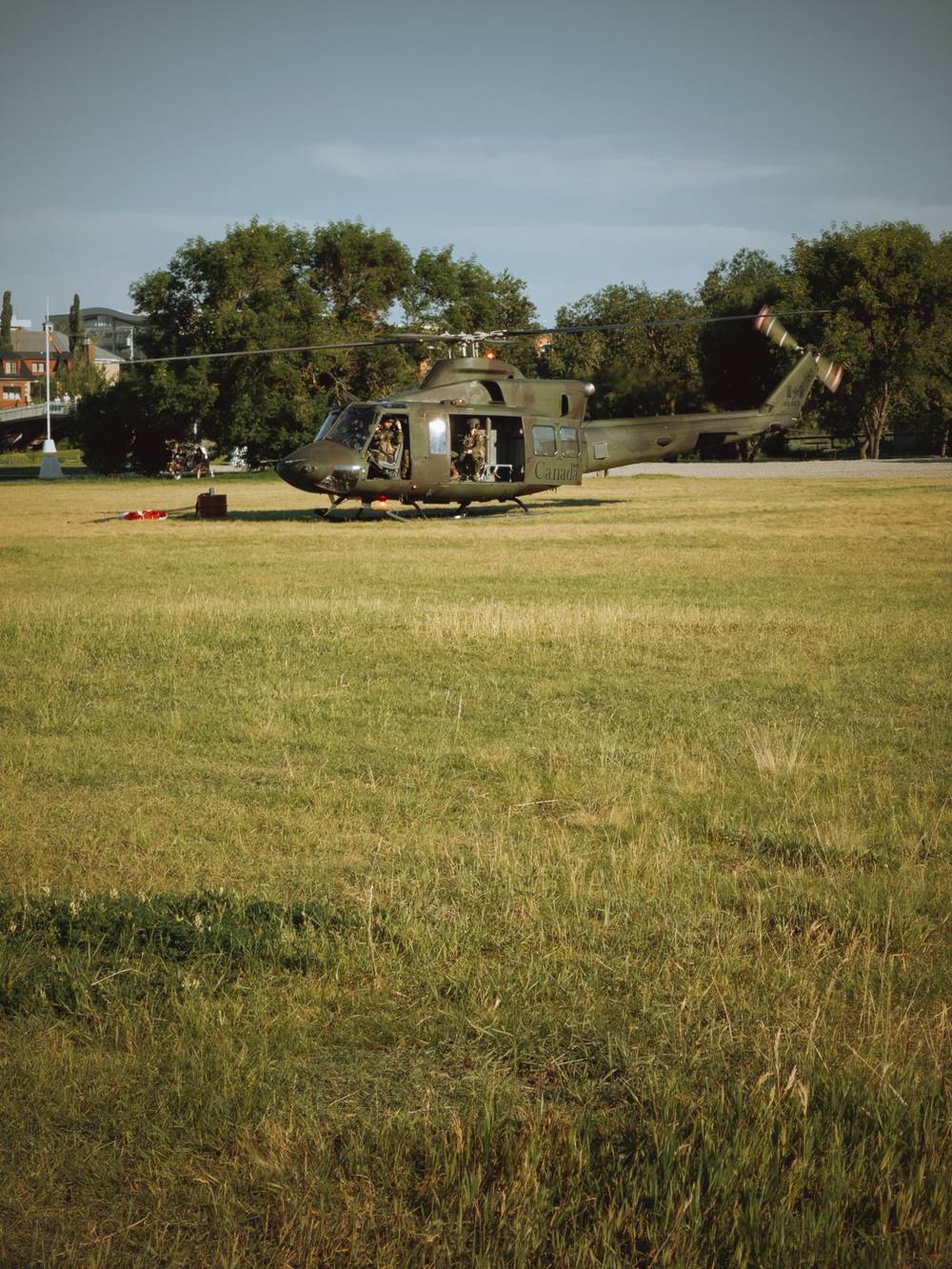 A photo of a military-style helicopter landing in a grassy field.