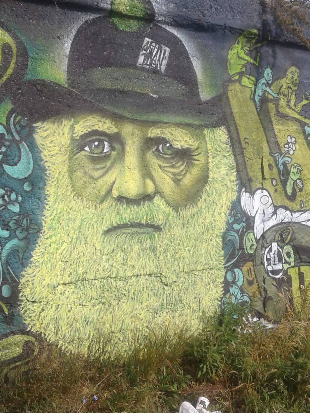 Street art of some guy with a bowler hat, a large beard, and green skin