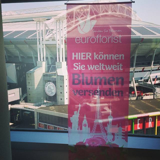 A large pink banner advertising Euroflorist flower delivery hanging on a stadium building.