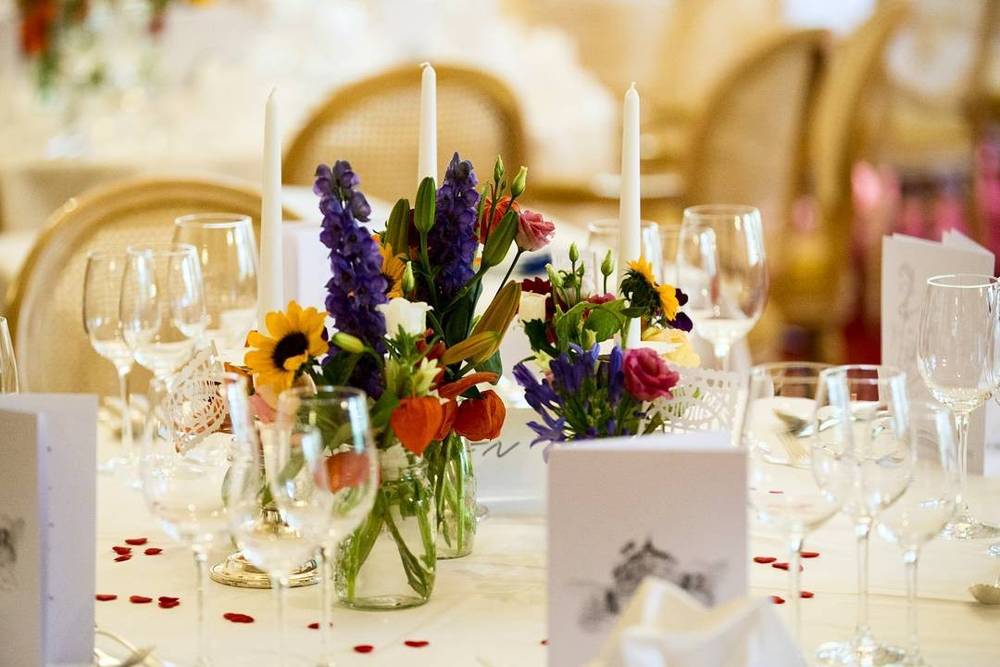 An elegant wedding table setting with candles, wine glasses, and a floral centerpiece.