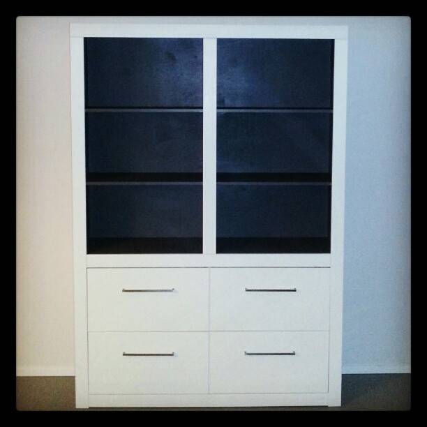 A finished white cabinet with glass doors and drawers, fully assembled.