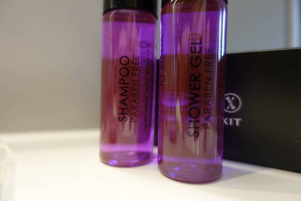 Two small purple shampoo and shower gel bottles labeled "paraben free" on a bathroom counter.