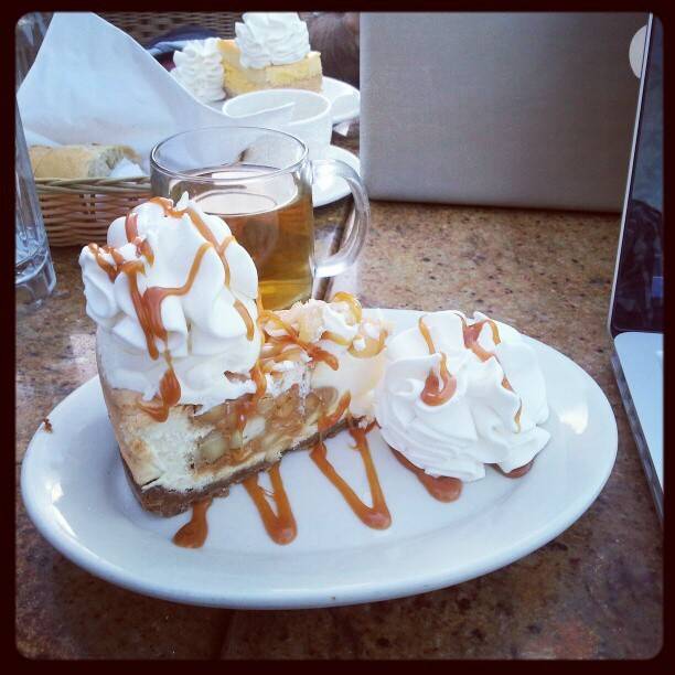 A slice of cheesecake drizzled with caramel and topped with whipped cream on a plate.