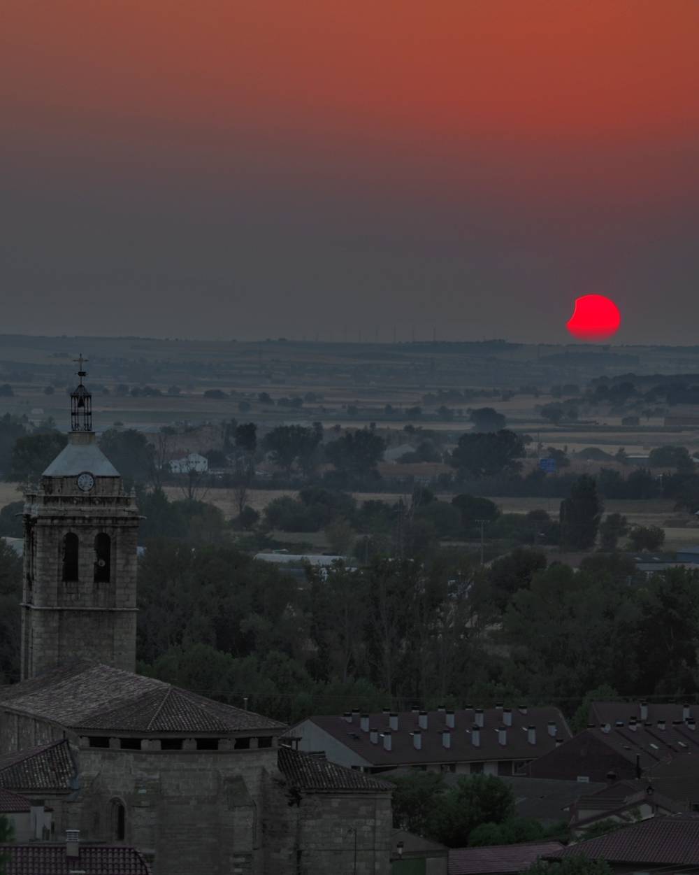 Town landscape in a sunset. The sun is partially eclipsed.