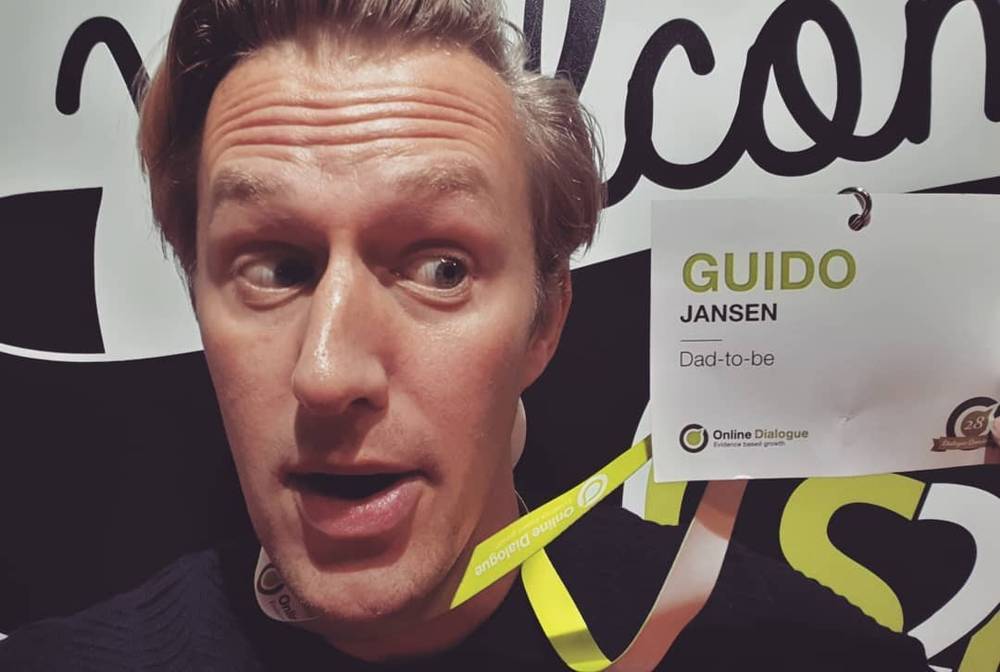 A close-up selfie making a surprised face, wearing a conference name badge reading 'Guido Jansen, Dad-to-be'.