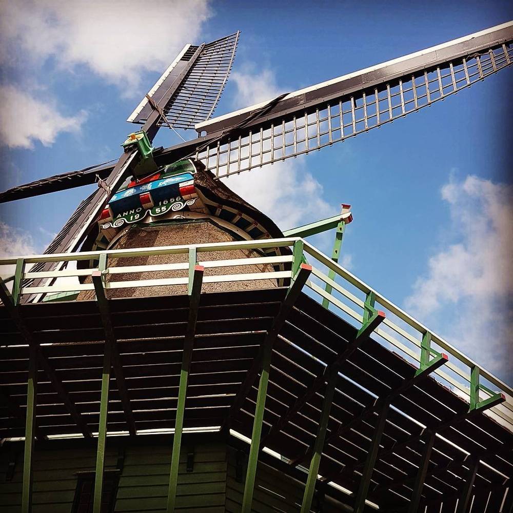 Close-up of a traditional Dutch windmill's sails and structure against a blue sky.