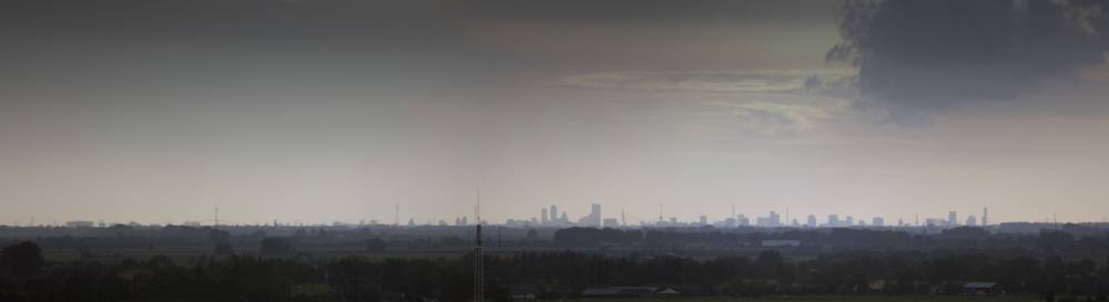 Rotterdam's hazy skyline is visible on the horizon, photographed from Utrecht.
