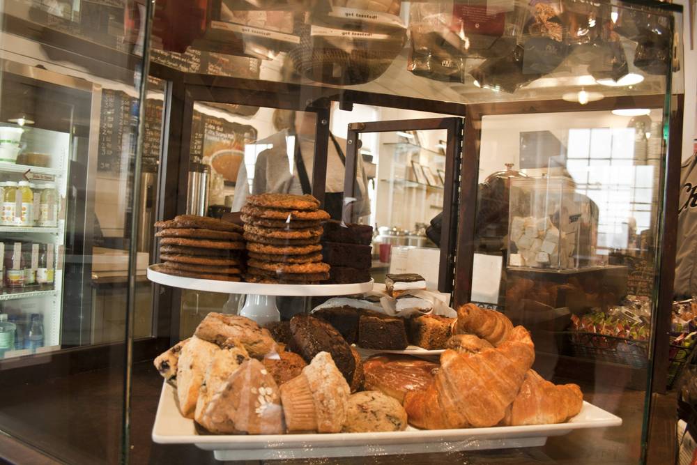 A bakery display case is stacked with cookies, croissants, muffins and scones.