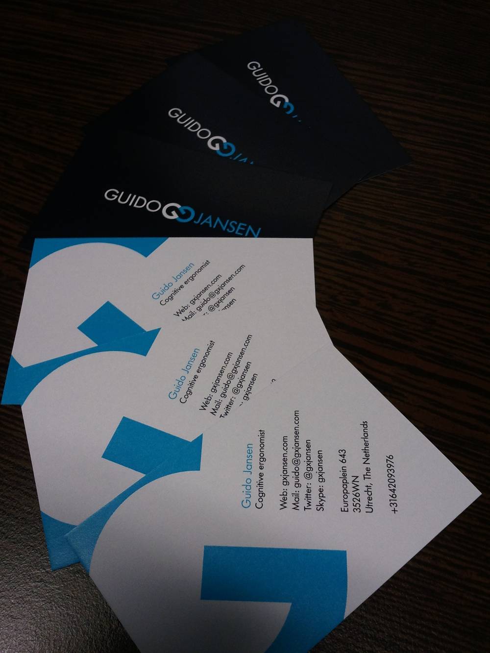 A fanned stack of dark blue business cards with a swirl logo lies on a table.