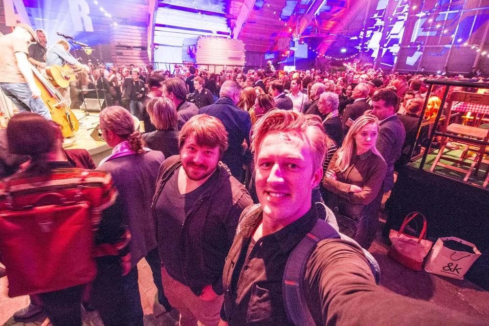 A wide selfie captures a larger group of colleagues posing together in the crowd at the party.