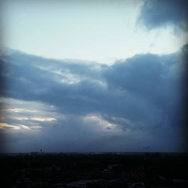 Dark storm clouds over a city skyline at dusk.