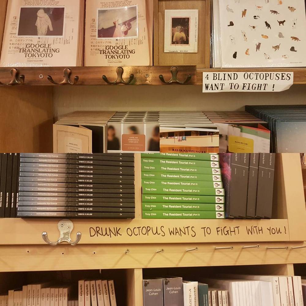 Shelves of travel guidebooks and postcards with a handwritten sign about octopuses.