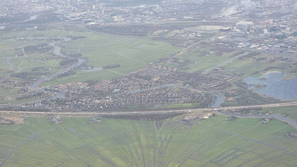 Aerial view descending into a valley town surrounded by green fields.