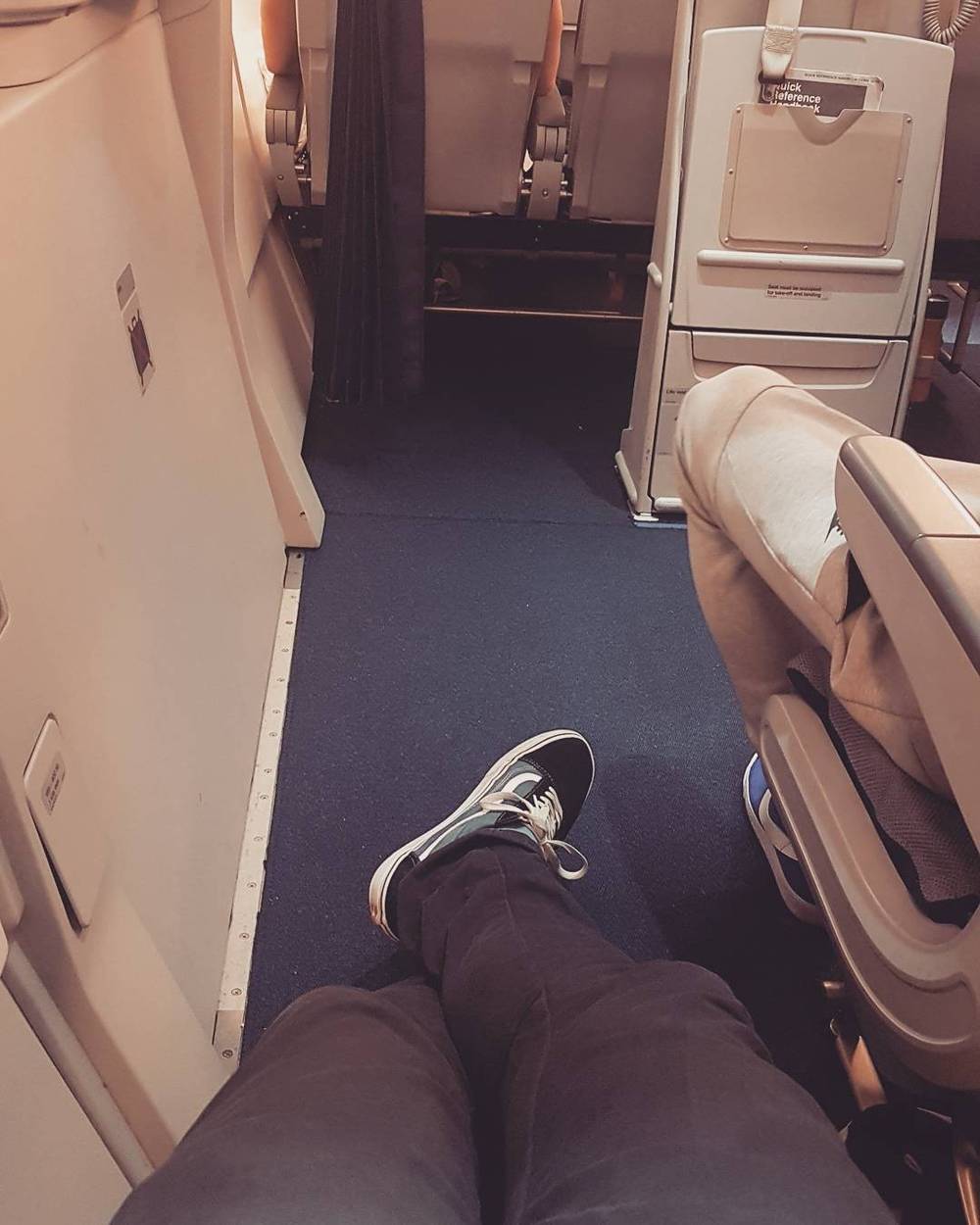 Legs stretched out with feet against the bulkhead wall of an airplane cabin.