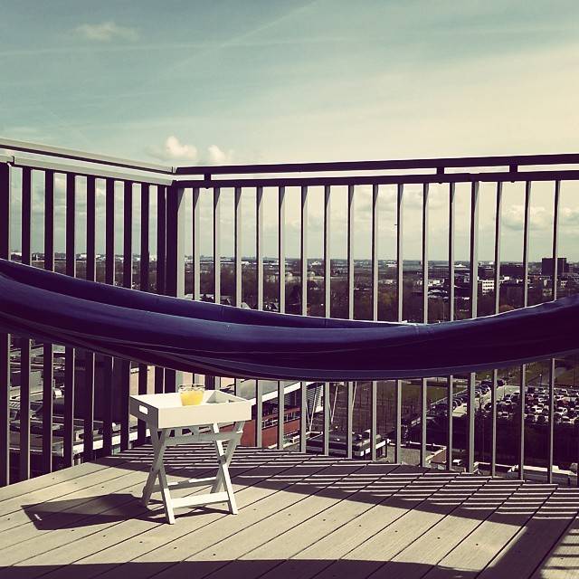 A striped hammock strung between railings on a balcony.