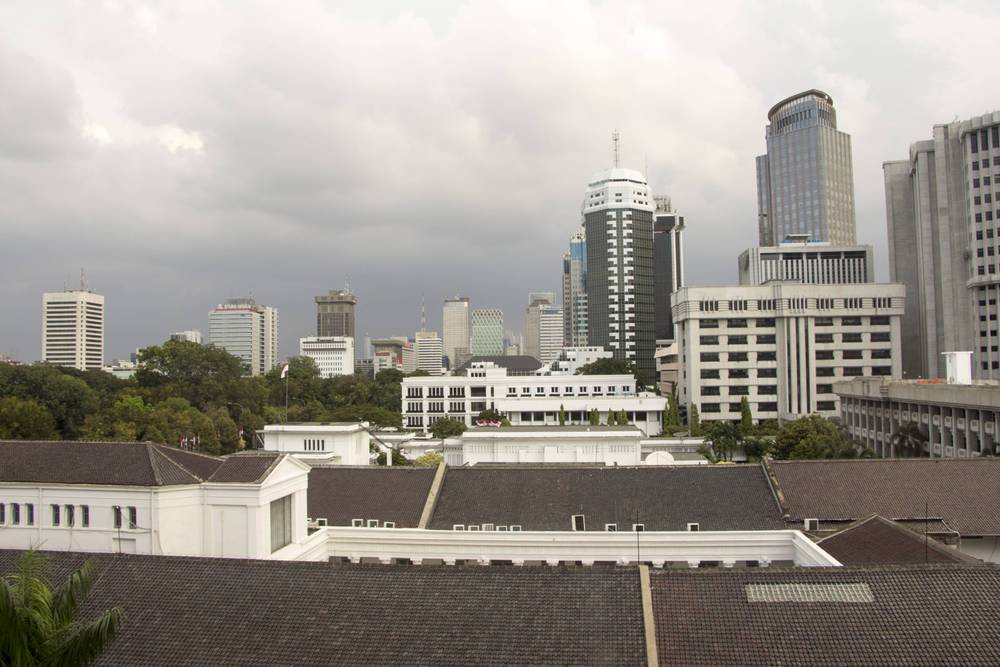 A rooftop view overlooks the white colonnaded museum building against the modern Jakarta skyline.