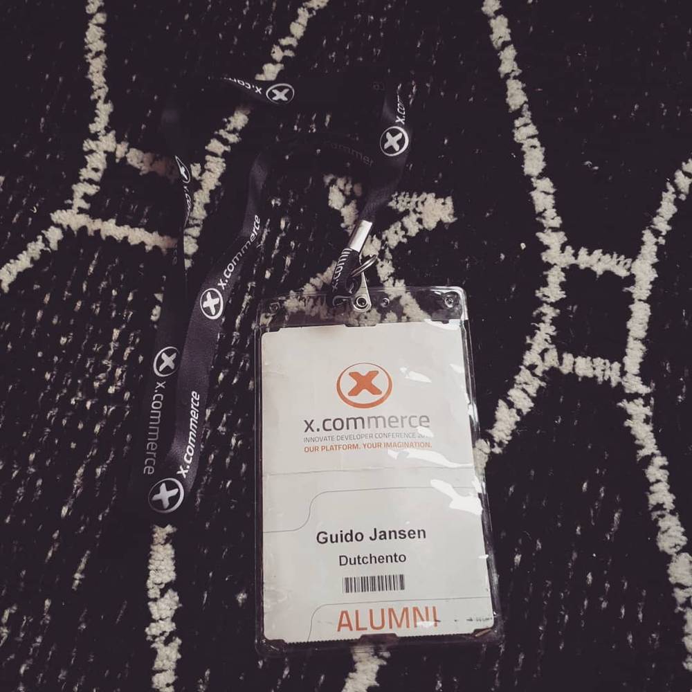 An x.commerce conference lanyard reading Guido Jansen, Dutchento, Alumni.