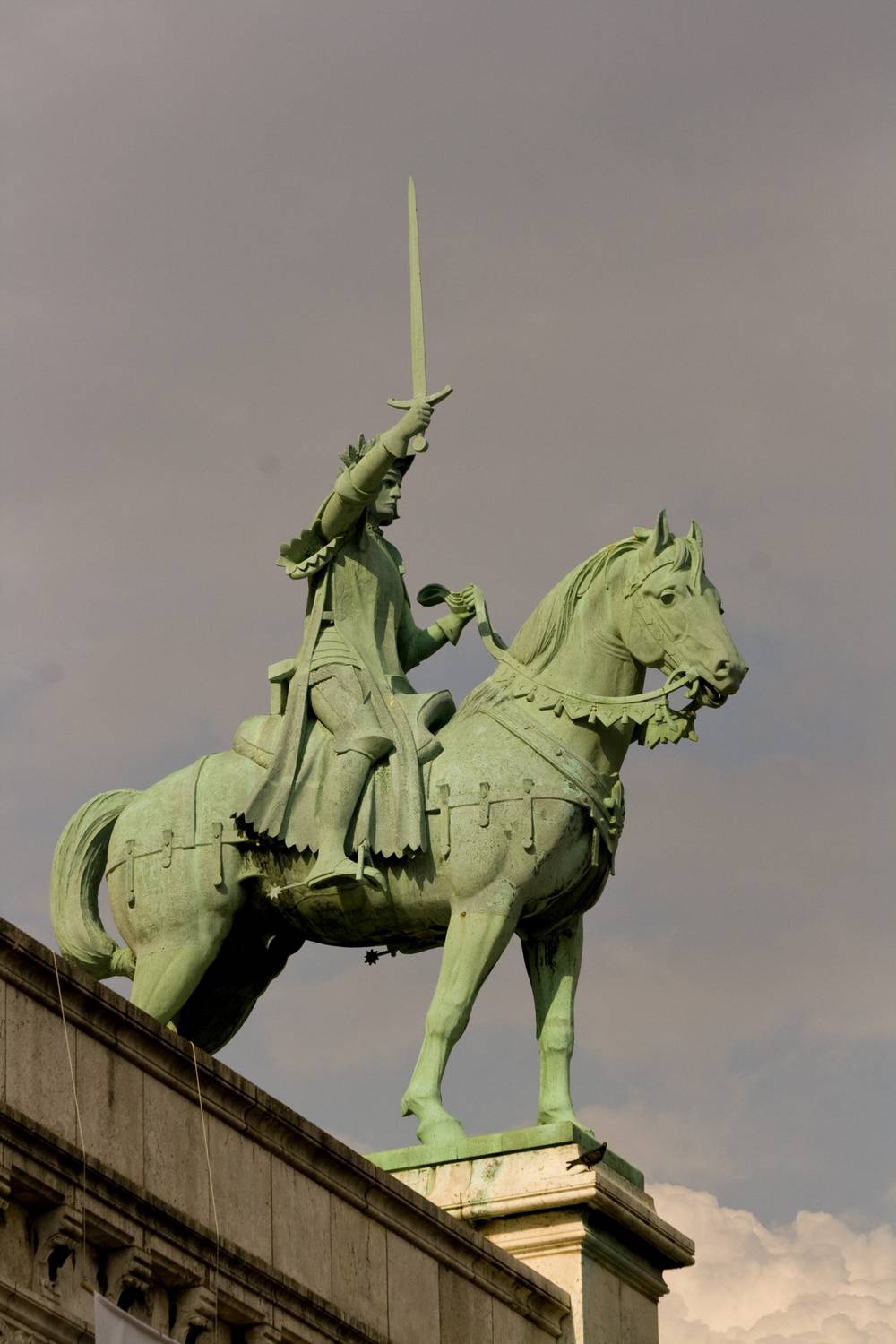 A close-up shows a green bronze statue of a knight on horseback holding a sword aloft.