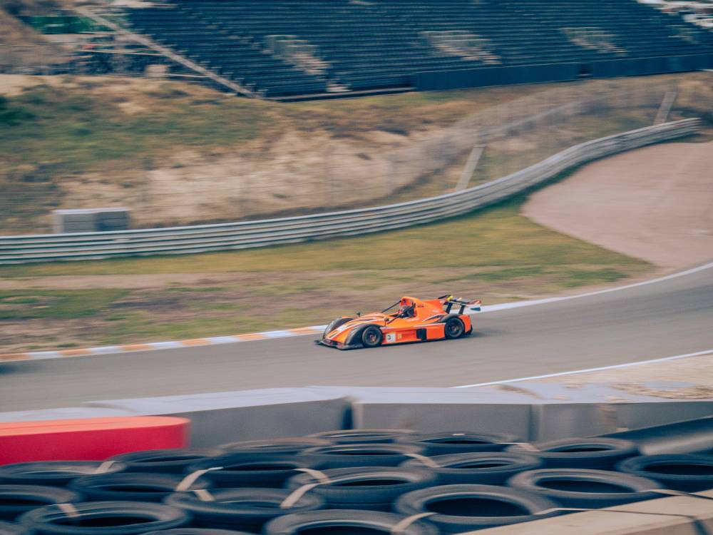 A orange race car driving around a corner.