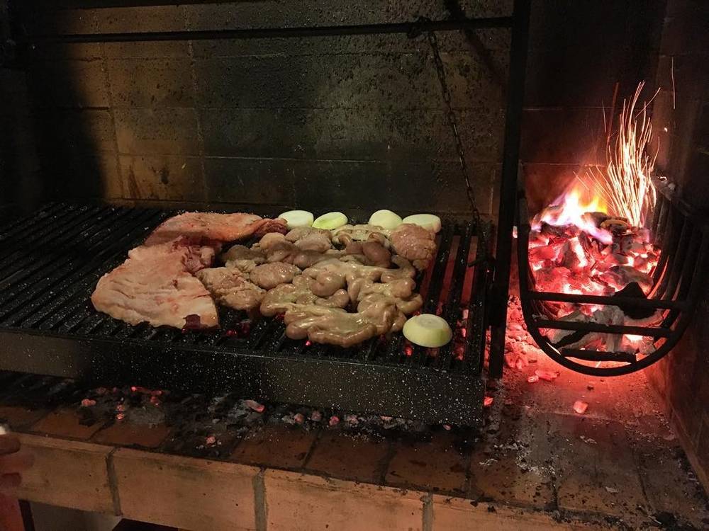 Meat and vegetables cooking on an open charcoal grill.