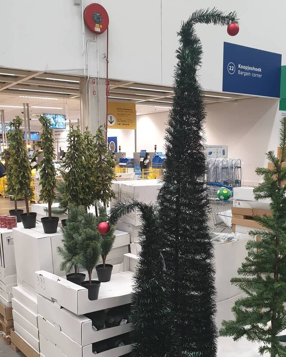A store display of small artificial Christmas trees for sale with price tags.