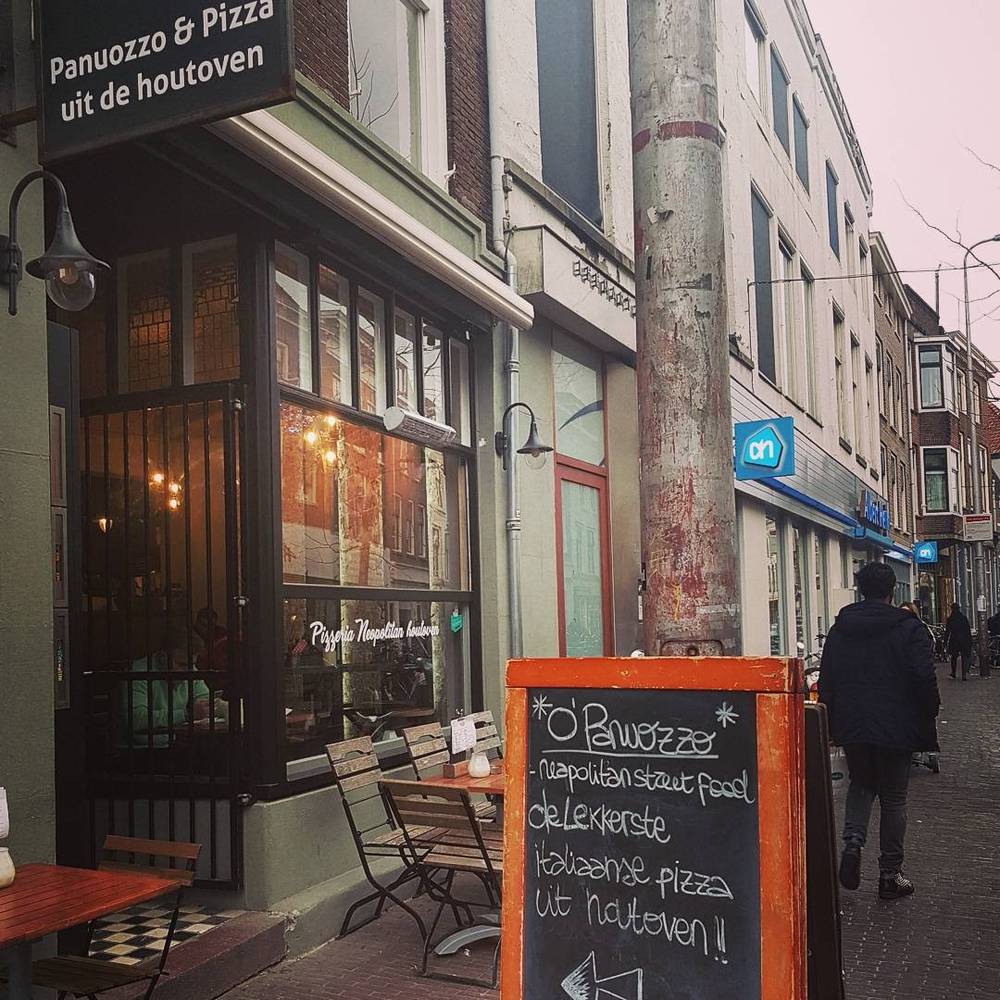 A pizza restaurant storefront with a chalkboard sign advertising Neapolitan street food.