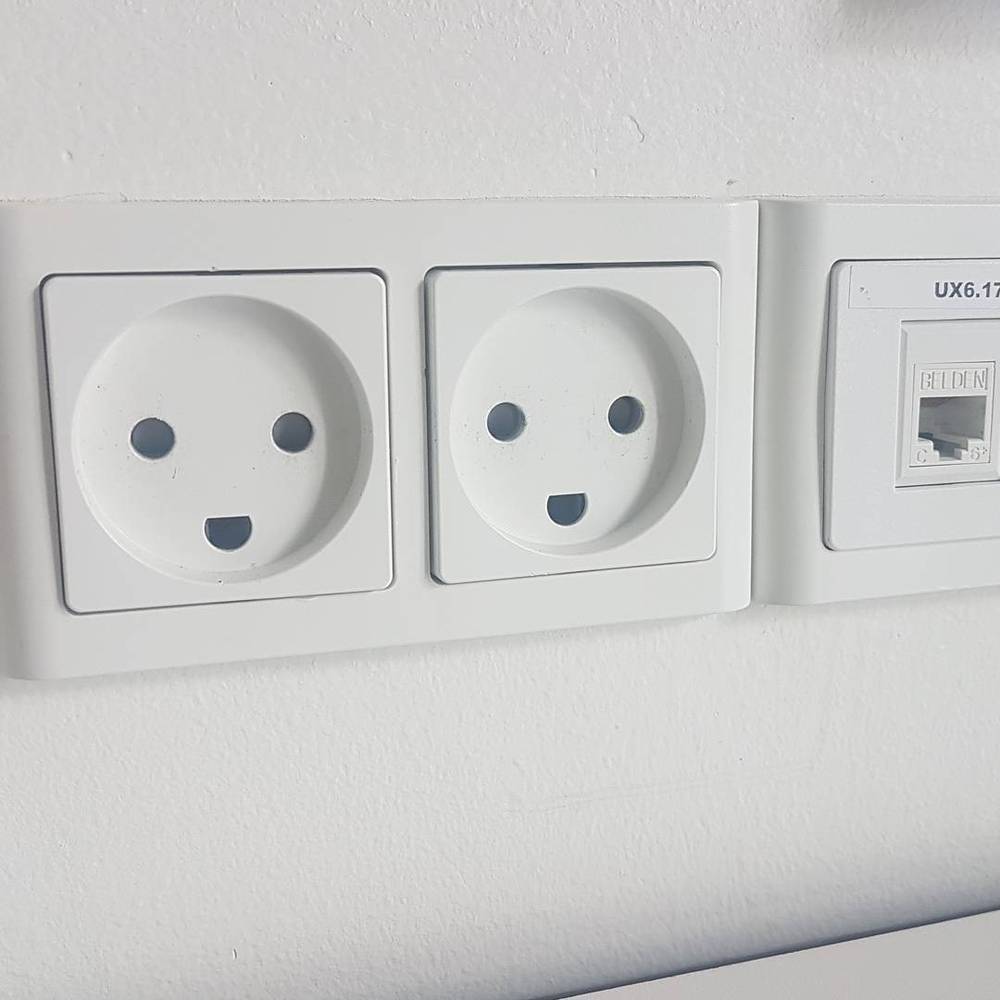 Two European wall power sockets whose shape forms smiley faces.