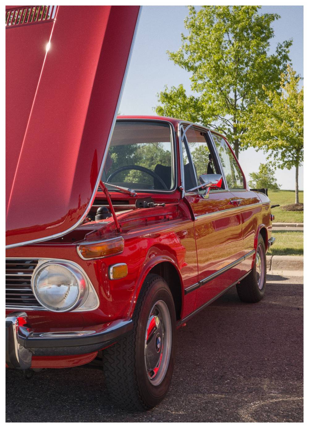 A partial front/side view of a classic red BMW with it's hood up