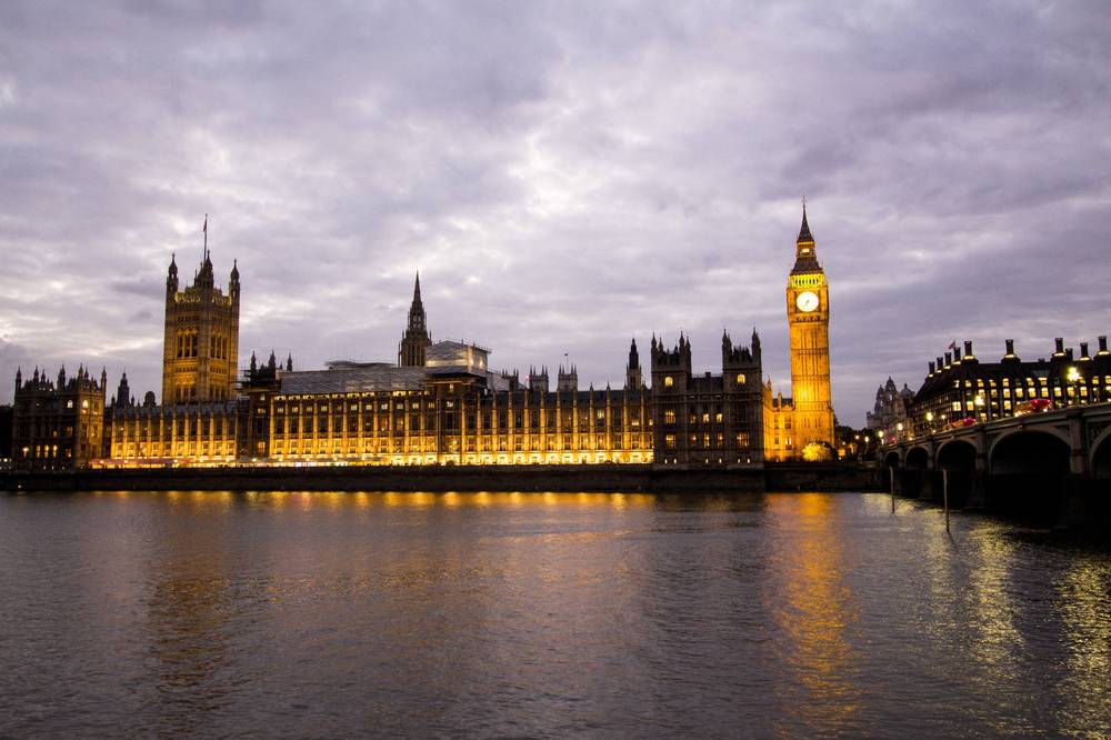 The Houses of Parliament and Big Ben glow gold across the Thames at dusk.