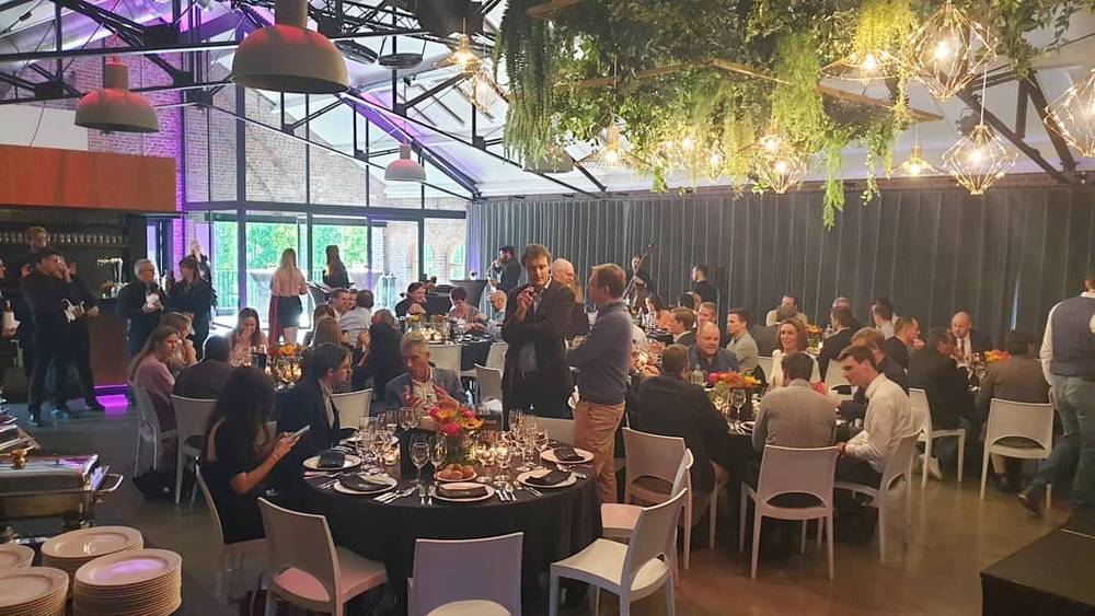 An elegant dinner event with round tables, string lights and mingling guests.