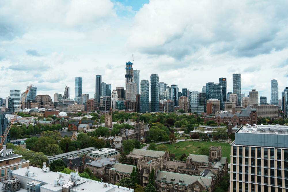 A photo of the Toronto skyline from the top of one of the University of Toronto buildings, showing the skyscrapers downtown and some of the greenery at UofT.